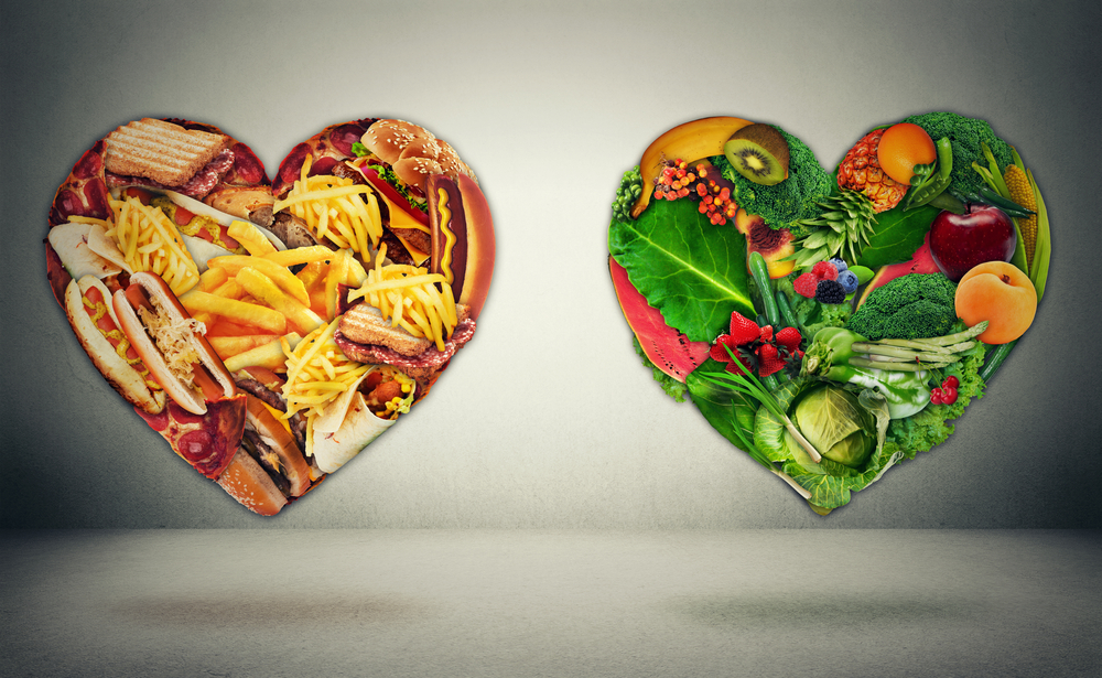 Dwa serca obrazujące cholesterol LDL i HDL: jedno wypełnione fast foodami, a drugie – warzywami i owocami